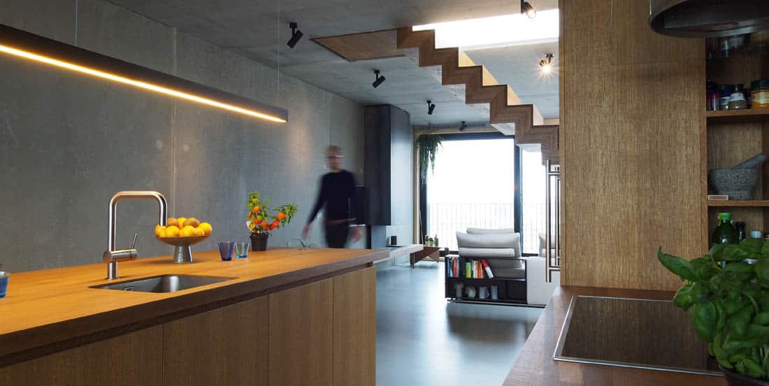 In het penthouse staan de keuken en trap vrij in de ruimte en houden het uitzicht naar alle kanten open. Een project in Amsterdam van MKA met binnenhuisarchitect Bergblick interieurarchitectuur.